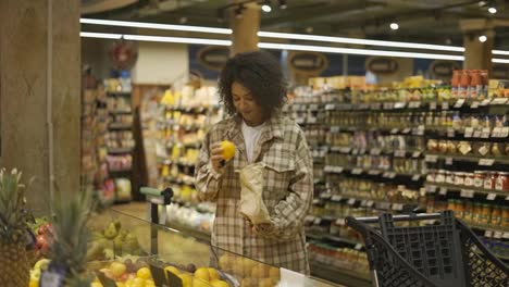 Afroamerikanische,-Stilvolle-Frau,-Die-Im-Supermarkt-Orangen-In-Eine-Papiertüte-Wählt