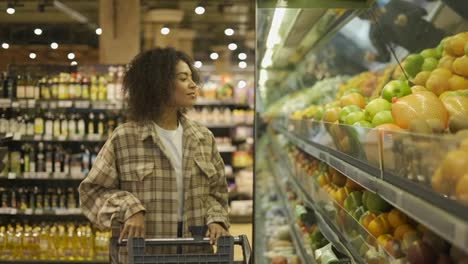 African-American-woman-choosing-pomelo-in-supermarket