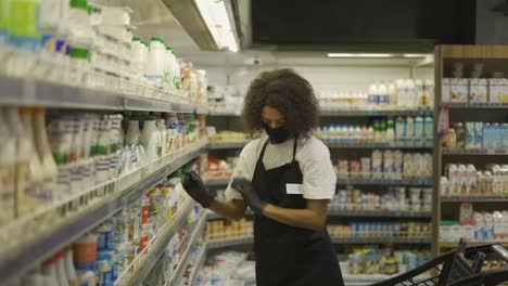 Female-worker-arranging-products-on-shelves-in-milk-department-in-food-store