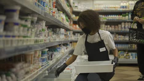 Female-worker-arranging-products-on-shelves-in-milk-department-in-supermarket,-slow-motion
