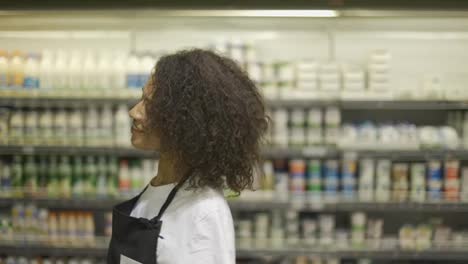 Cheerful-worker-in-black-apron-dancing-in-supermarket,-having-fun-during-work