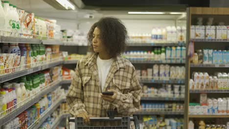 Afroamerikanische-Dame,-Die-Im-Supermarkt-Die-Einkaufsliste-Auf-Dem-Smartphone-überprüft