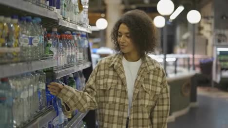 Mujer-Negra-Haciendo-Compras-En-El-Supermercado,-Buscando-Botellas-De-Agua,-Cámara-Lenta