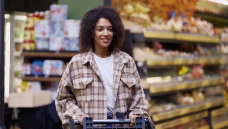 Portrait-of-an-african-american-woman-walks-through-supermarket-with-cart