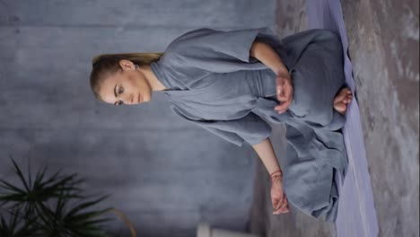 Elegant-woman-in-stylish-blue-robe-sitting-in-lotus-pose