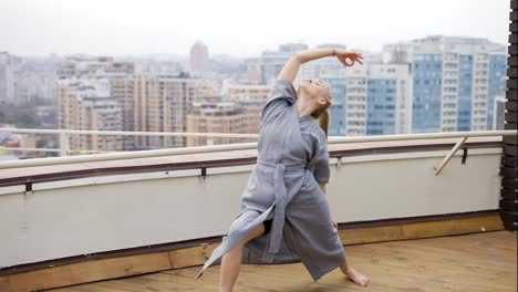 Elegante-Frau-Im-Stilvollen-Blauen-Gewand,-Die-Yoga-Auf-Der-Terrasse-Praktiziert