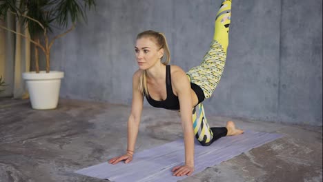 Blonde-woman-professionally-doing-exercising-on-mat-in-studio