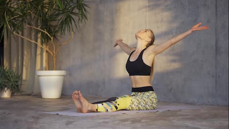 Female-coach-yoga-practicing-yoga-or-stretching-in-loft-studio-on-mat