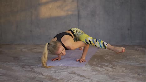 Yogi-woman-practicing-complex-yoga-exercise-in-loft-studio-on-mat