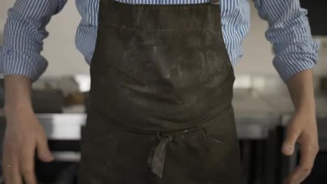 Male-baker-wipes-his-hands-on-and-apron-from-flour-and-puts-hands-on-hips