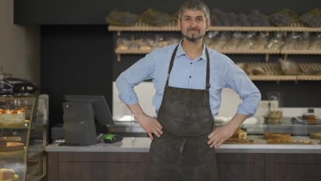 Friendly-Male-baker-wipes-his-hands-on-an-apron-from-flour-and-puts-hands-on-hips