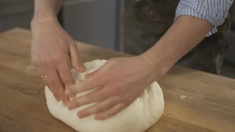 Nahaufnahme-Der-Hände-Eines-Leitenden-Bäckerkochs,-Der-Mehl-Auf-Den-Teig-Aufträgt,-Eines-Alten-Mannes,-Der-Teig-Knetet-Und-Auf-Traditionelle-Weise-Brot-Backt