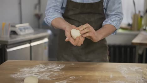 Baker-kneads-dough-and-making-bread.-Chef-prepares-dough-with-flour.-Hands-kneading-the-dough-on-table.-Baker-hands-close-up.-Preparing-bread.-Male-hands-close-up