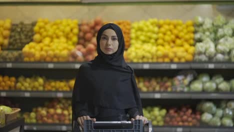 Retrato-De-Una-Mujer-Musulmana-Comprando-Comestibles-En-El-Supermercado,-Empujando-El-Carro