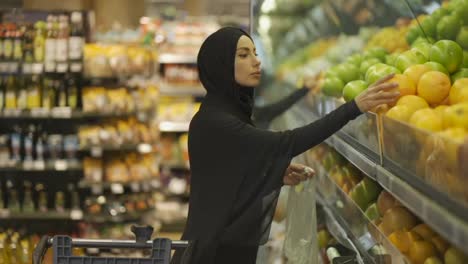 Muslim-women-shopping-for-groceries,-taking-fruits-from-the-shelf