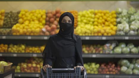 Woman-in-hijab-doing-grocery-shopping-in-supermarket,-wearing-mask