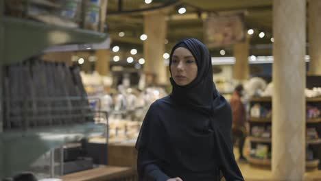 Woman-in-hijab-takes-pile-of-products-from-the-shelf-in-the-supermarket,-slow-motion