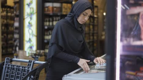 Frau-Im-Hijab-Und-Nimmt-Produkt-Aus-Dem-Gefrierschrank-Im-Supermarkt