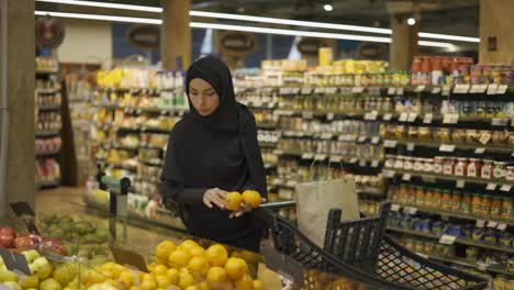 Mujer-Musulmana-Comprando-Comestibles,-Tomando-Limones-Del-Pasillo-De-Frutas