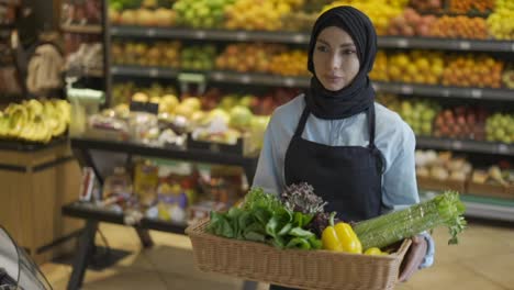Muslimische-Frau-Im-Hijab-Geht-Mit-Einem-Korb-Mit-Frischem-Gemüse-Im-Supermarkt-Spazieren,-Aus-Nächster-Nähe