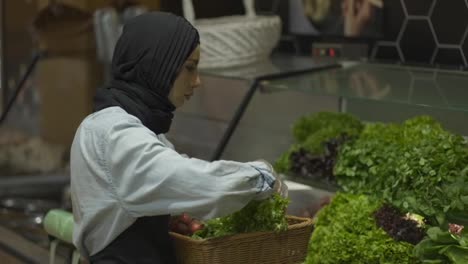 Dame-Im-Hijab-Füllt-Das-Frische-Grün-Im-Regal-Im-Supermarkt-Nach