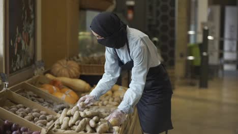 Woman-in-niqab-refill-the-potatos-on-the-stock-at-the-supermarket