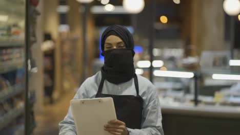 Porträt-Einer-Muslimischen-Supermarktarbeiterin,-Die-Mit-Einem-Tablet-In-Der-Hand-Steht