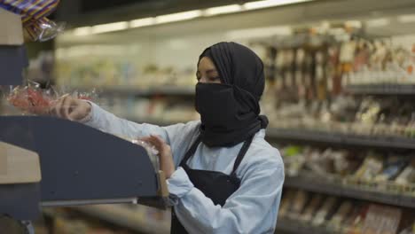 Mujer-Con-Bufanda-Negra-Trabajando-En-La-Tienda,-Inspeccionando-Estantes-En-La-Tienda-En-El-Departamento-De-Panadería