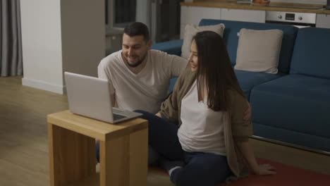 Pregnant-woman-and-man-talking-by-video-call-using-laptop