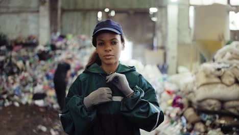 Porträt-Einer-Jungen-Afroamerikanischen-Frau-In-Einer-Recyclinganlage.-Müll-Im-Hintergrund.-Umweltschutz