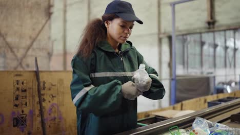 Afro-american-girl-sorting-bottles-at-a-garbage-recycling-plant.-Pollution-control