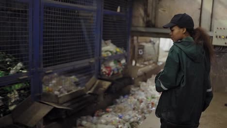 Eine-Junge-Afroamerikanerin-überprüft-Ein-Förderband-In-Einer-Recyclinganlage.-Umweltschutz