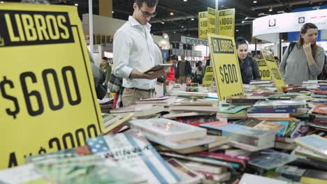 Low-angle-static-view-of-well-dressed-young-professionals-browsing-bookfair-discount-section