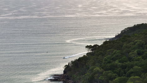 Drone-View-Of-Ocean-Jetskiing-Around-Headland-Of-Noosa-Mainbeach-At-Sunrise,-4K-Slow-Motion-Australia