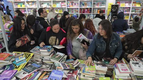 Pan-across-people-sharing-new-books-that-they-find-at-book-fair-discount-table