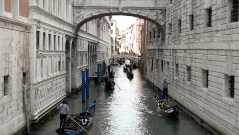 Blick-Auf-Gondeln-Mit-Touristen,-Die-Unter-Der-Seufzerbrücke-Am-Rio-Del-Palazzo-In-Venedig-Vorbeifahren