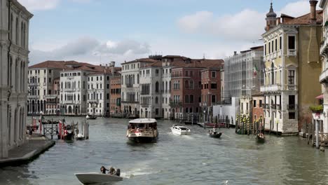 The-famous-gondolas-and-tour-boats-going-about-their-day-on-the-busy-waters-of-the-Grand-Canal,-an-overhead-view-from-the-Rialto-Bridge,-Venice,-Italy