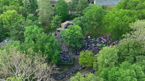 Aerial-footage-of-a-large-gathering-at-a-park-amphitheater-on-a-sunny-summer-day