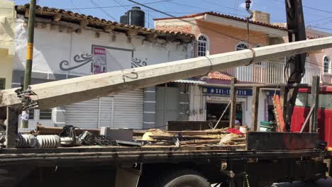 Concrete-utility-pole-and-transformers-loaded-on-construction-truck,-Mexico