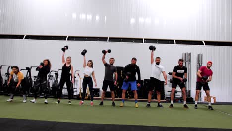 Group-of-people-lifting-a-heavy-dumbbell-in-the-crossfit-challange-class