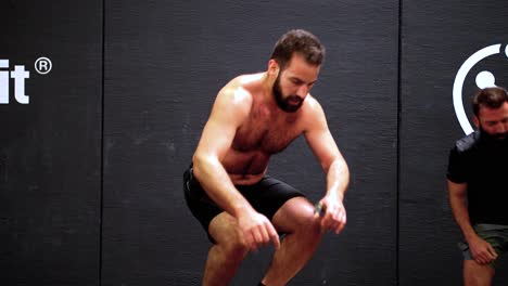 Un-Hombre-Musculoso-Sin-Camisa-Saltando-Encima-De-La-Caja-Del-Gimnasio-Mientras-Intenta-Un-Desafío-De-Crossfit