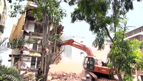 Urban-scene-with-men-looking-at-excavator-demolishing-small-building