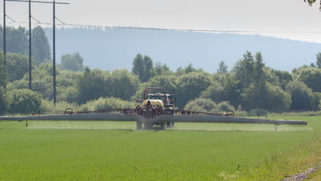 Pesticide-crop-spraying-on-farm-land-with-sprayer-tractor,-long-shot