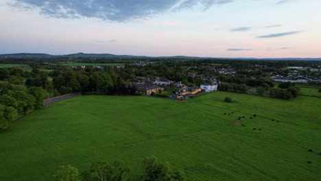 Backward-aerial-view-over-St-Nicholas-Church-and-Augustinian-Friary-in-Adare,-Ireland