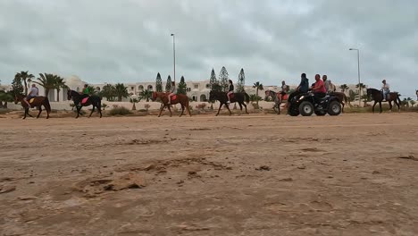 Low-angle-ground-surface-point-of-view-of-caravan-of-horses-carriages-and-camels-across-Djerba-desert,-Tunisia