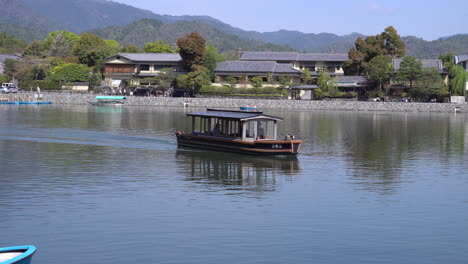 KYOTO,-JAPAN---April-4,-2023:-Boats-in-Katsura-River-in-Arashiyama-district-with-cherry-blossom-in-spring-time