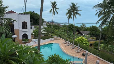 Timelapse-Overlooking-a-Swimming-Pool-with-Palm-Trees-on-the-Island-of-Koh-Samui,-Thailand