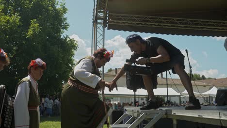 Cameraman-helps-older-ladies-onto-festival-stage-at-Bulgarian-cultural-event