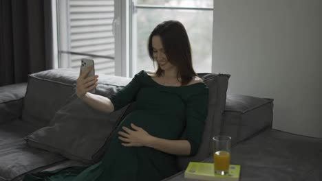 Pregnant-woman-video-chatting-on-mobile-phone-at-home