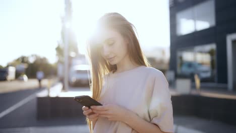 Young-woman-in-a-bright-sunlight-uses-phone